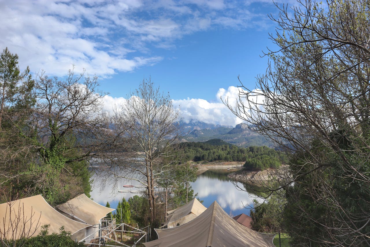 Beautiful mountainous landscape with tents by a serene lake under a blue sky.